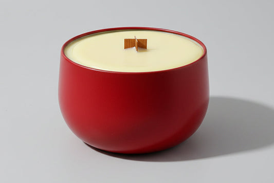 Red candle holder with a white candle on a wooden surface